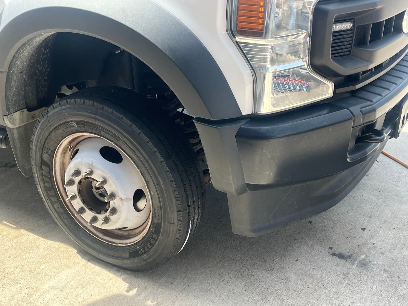 Close-up of a commercial semi-truck tire being serviced by K & W Mobile Tire Service — showing tread condition, DOT date code, and sidewall inspection
