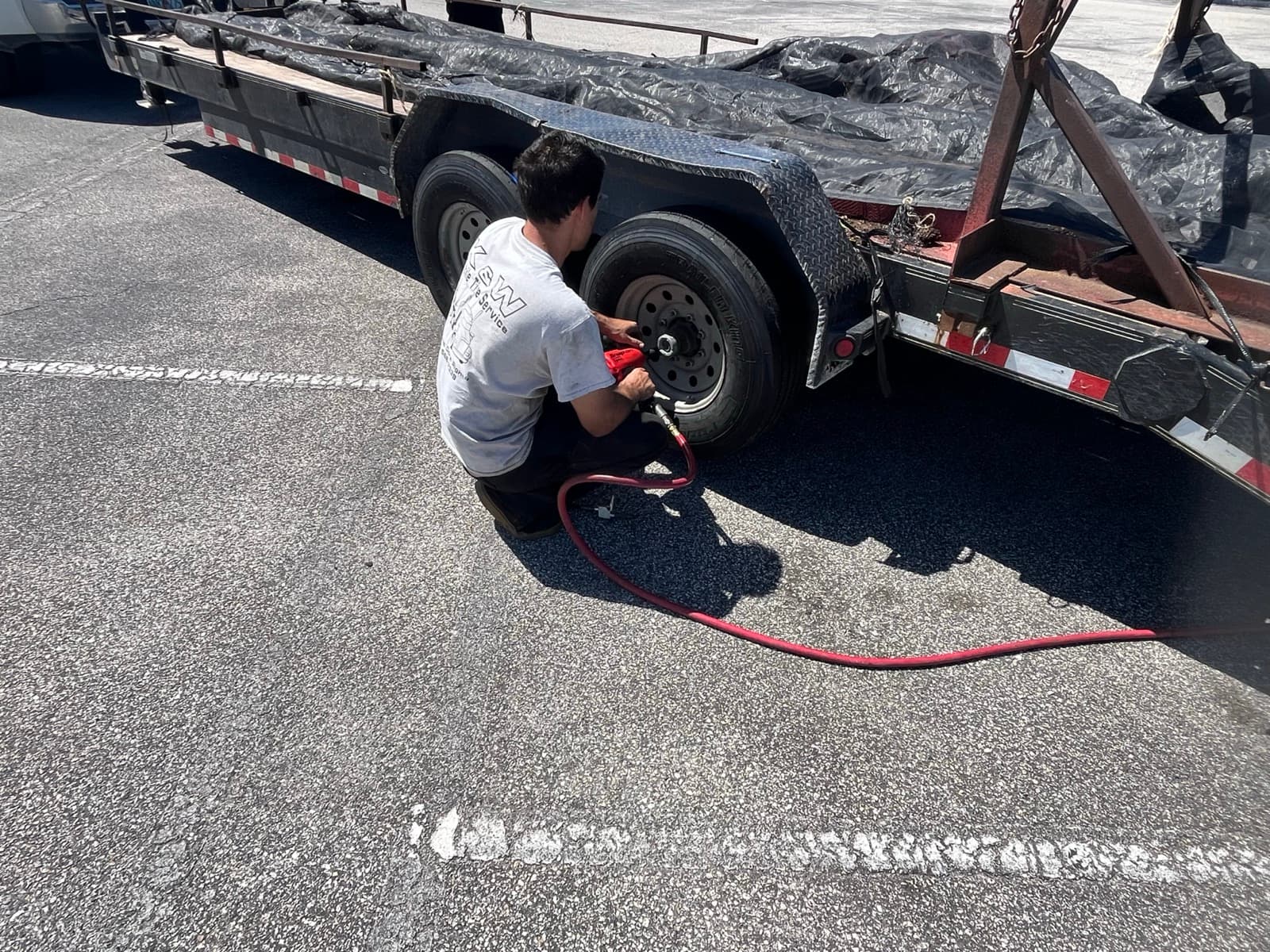 Utility trailer receiving on-site mobile tire repair from K & W Mobile Tire Service in Central Florida — ST trailer tires replaced at storage lots and driveways